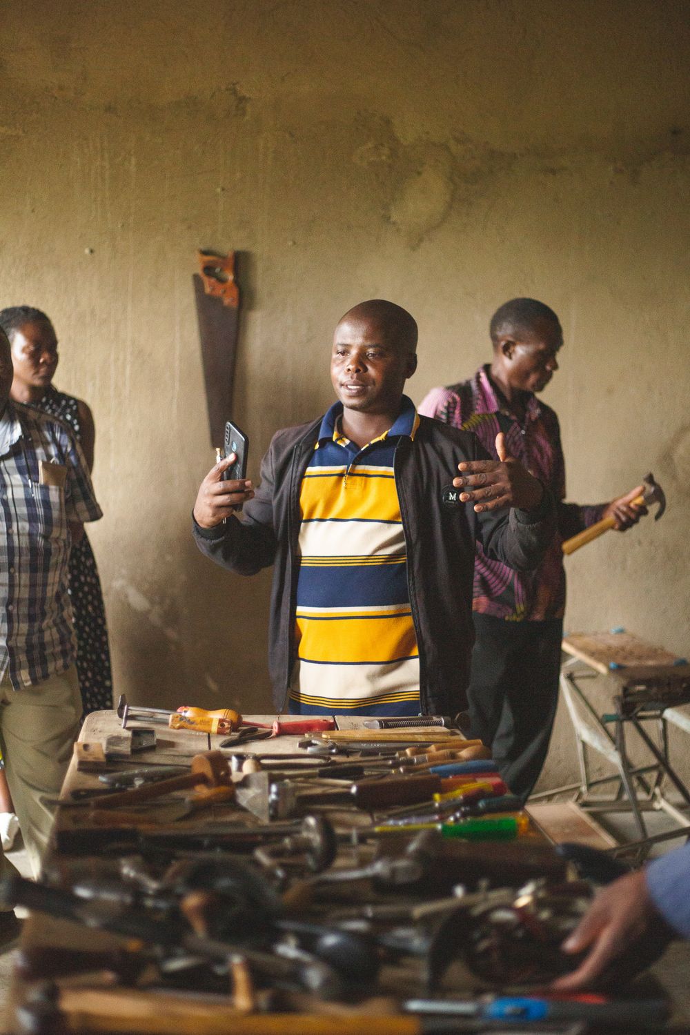 Formateur montrant un outil à des artisans à Kasese, Ouganda